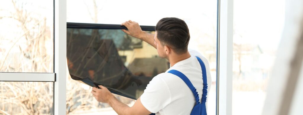A technician installing glare reducing film on a home.
